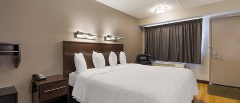 Une chambre d’hôtel avec un grand lit, des tables de chevet, un téléviseur à écran plat, un four à micro-ondes et une fenêtre avec des rideaux.