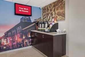 A hotel room with a large mural of a cityscape, a coffee machine, and a sign indicating free Wi-Fi in all rooms. - Red Roof Inn PLUS+ Nashville Airport (Nashville)