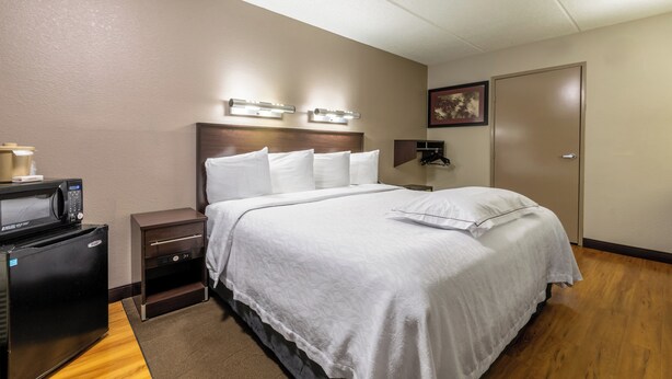A hotel room with a bed, bedside tables, a microwave, and a door. - Red Roof Inn PLUS+ Nashville Airport (Nashville)