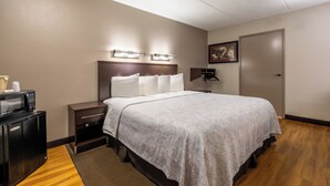 A hotel room with a bed, bedside tables, a microwave, and a door. - Red Roof Inn PLUS+ Nashville Airport (Nashville)