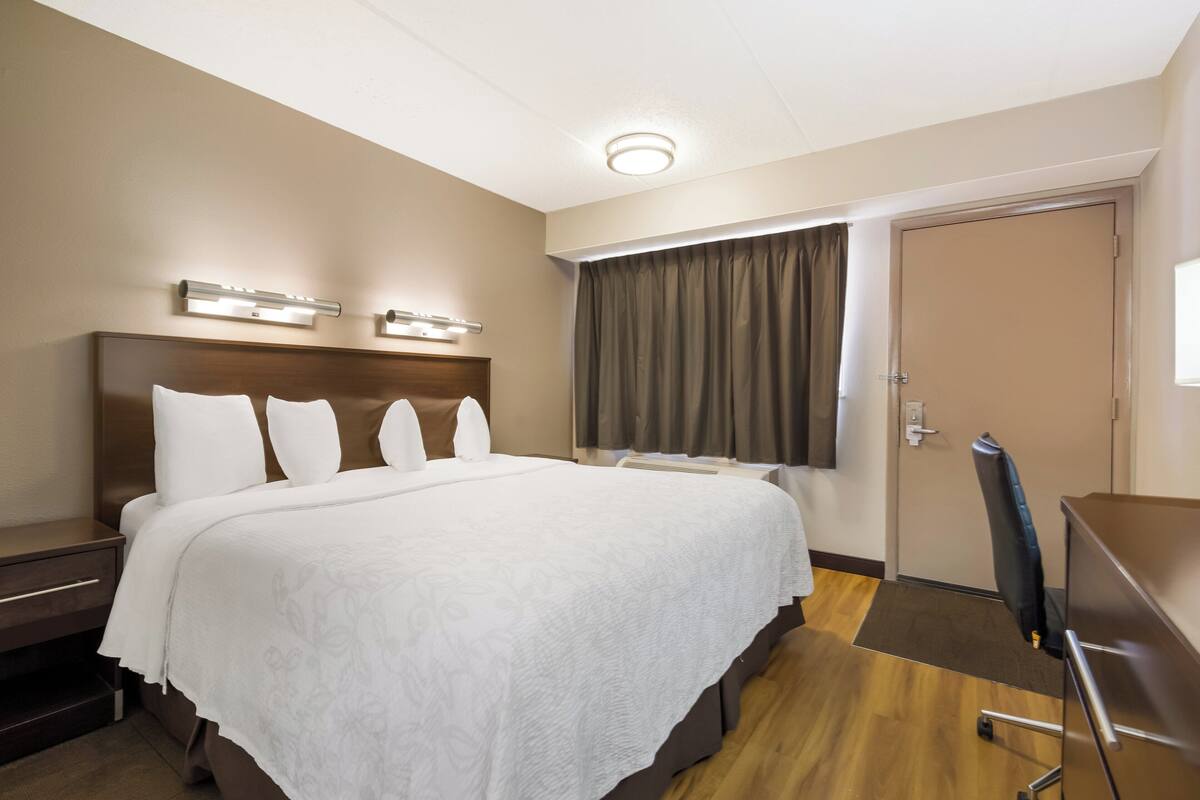 A hotel room with a large bed, bedside tables, a desk, and a chair.