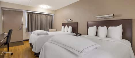 A hotel room with two beds, a desk, and a chair.