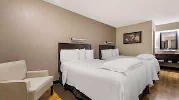 Una habitación de hotel con dos camas, una silla, un escritorio y un espejo.