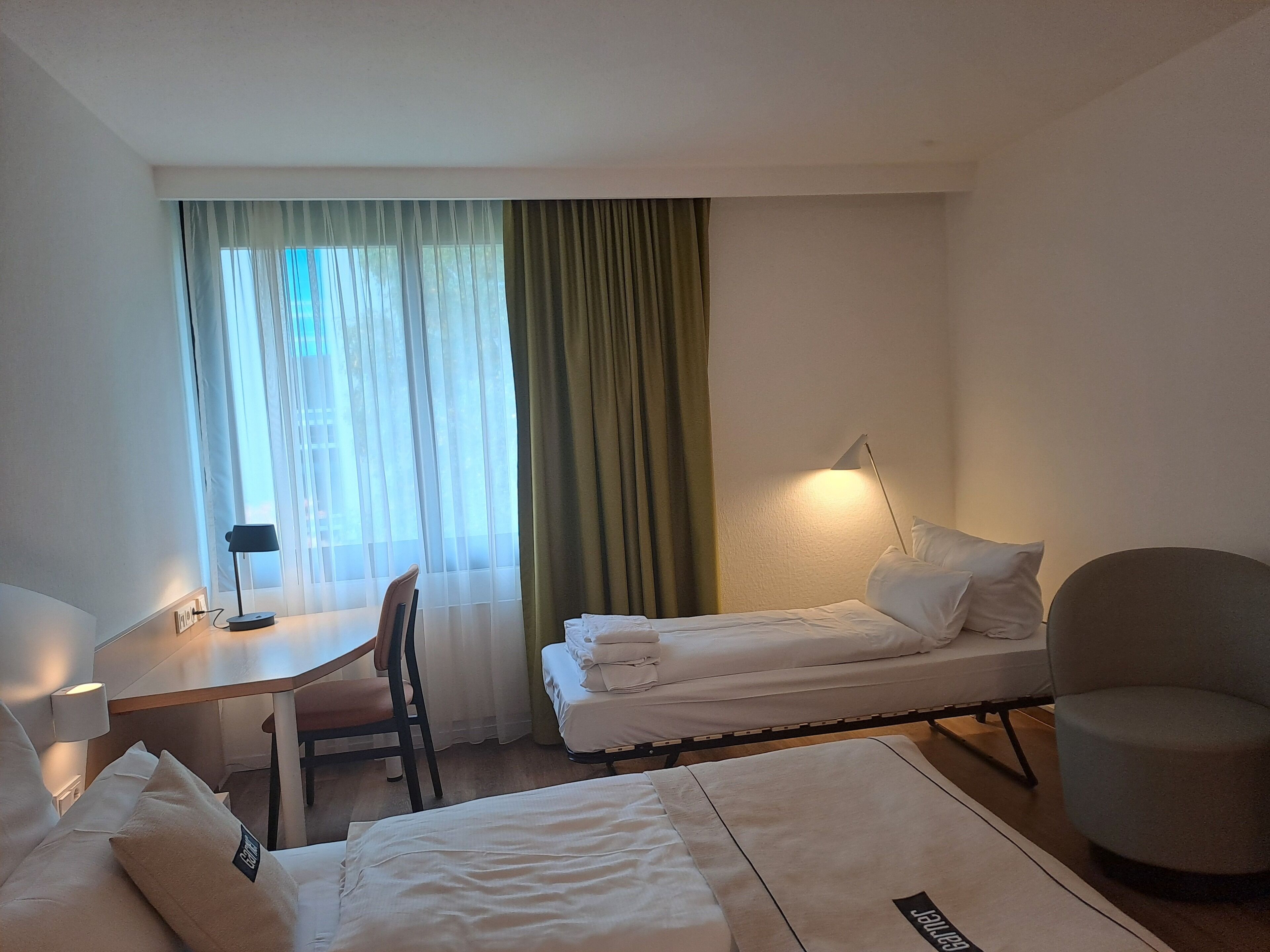 Ein Hotelzimmer mit Bett, Schreibtisch, Stuhl und Lampe.