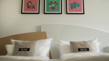 Ein Hotelzimmer mit einem Bett, zwei Kissen und drei gerahmten Bildern an der Wand.