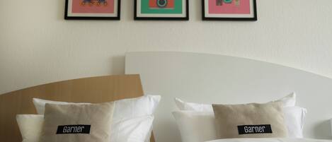 Habitación de hotel con una cama, dos almohadas y tres cuadros en la pared.