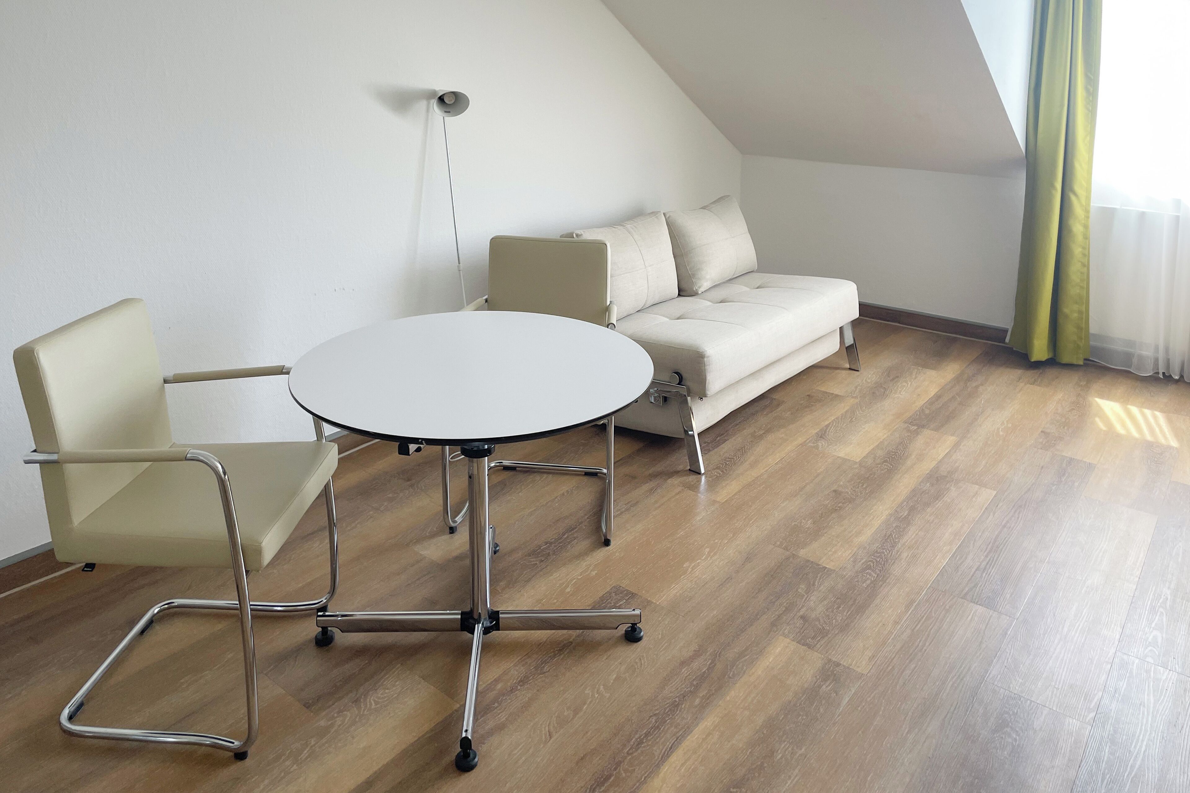 Una habitación con una mesa redonda, dos sillas, un sofá y una lámpara.