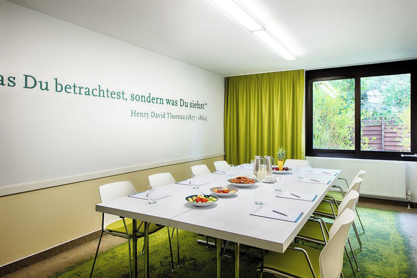 A conference room with a long table, chairs, and a projector screen displaying text.
