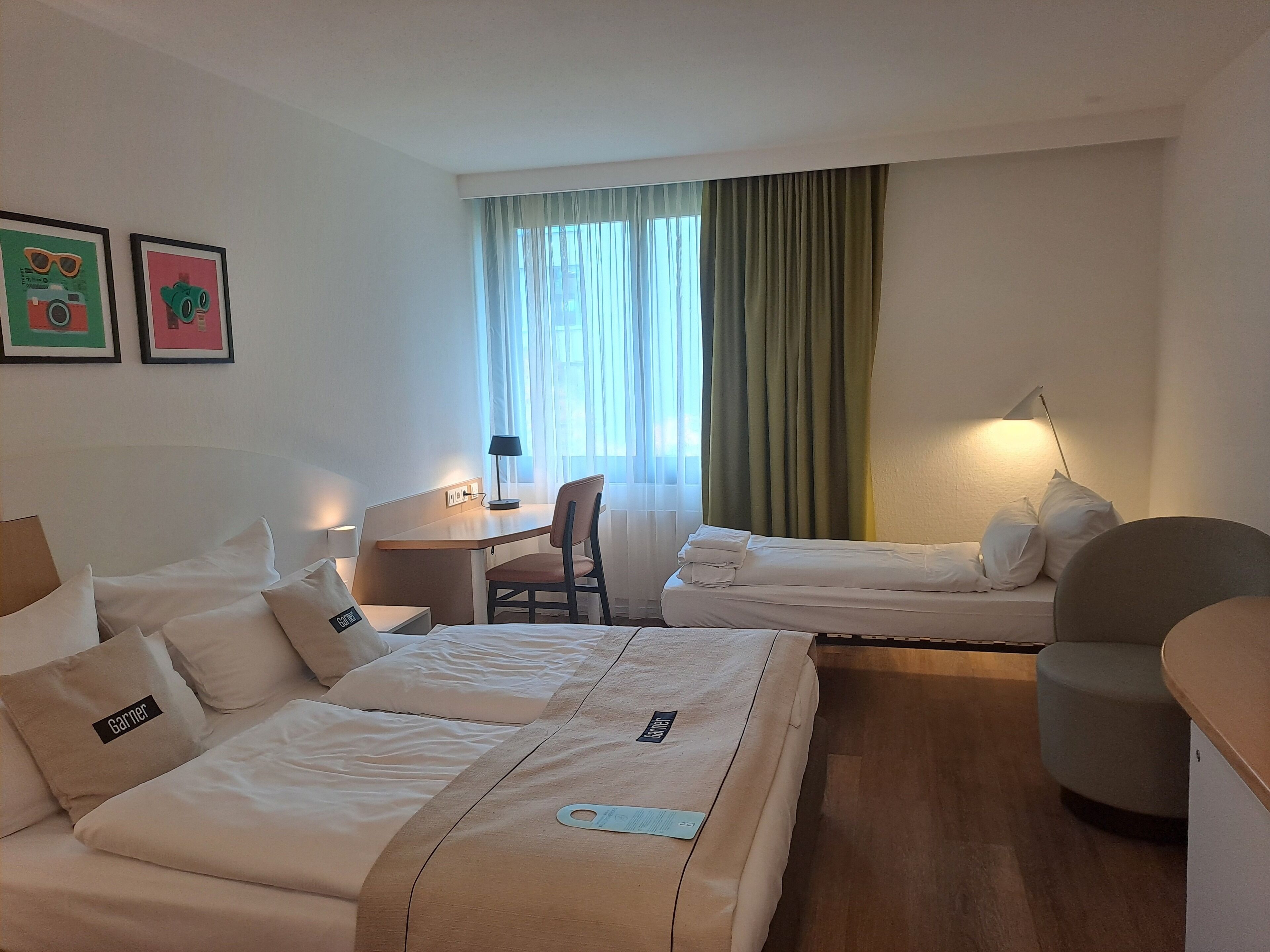 Een hotelkamer met twee bedden, een bureau, een stoel en een lamp.