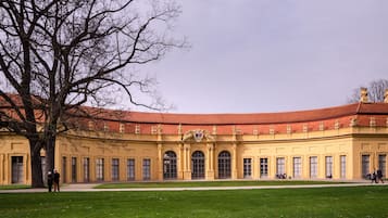 A large, yellow building with a curved roof and statues on the roofline.