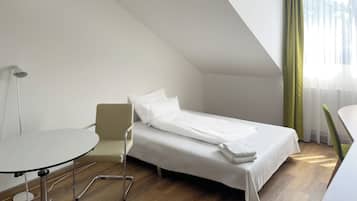 Une chambre d’hôtel moderne avec un lit simple, une petite table et une chaise.