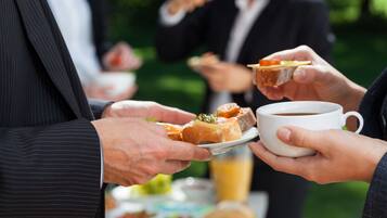 A group of people at an outdoor dining area with food and beverages.