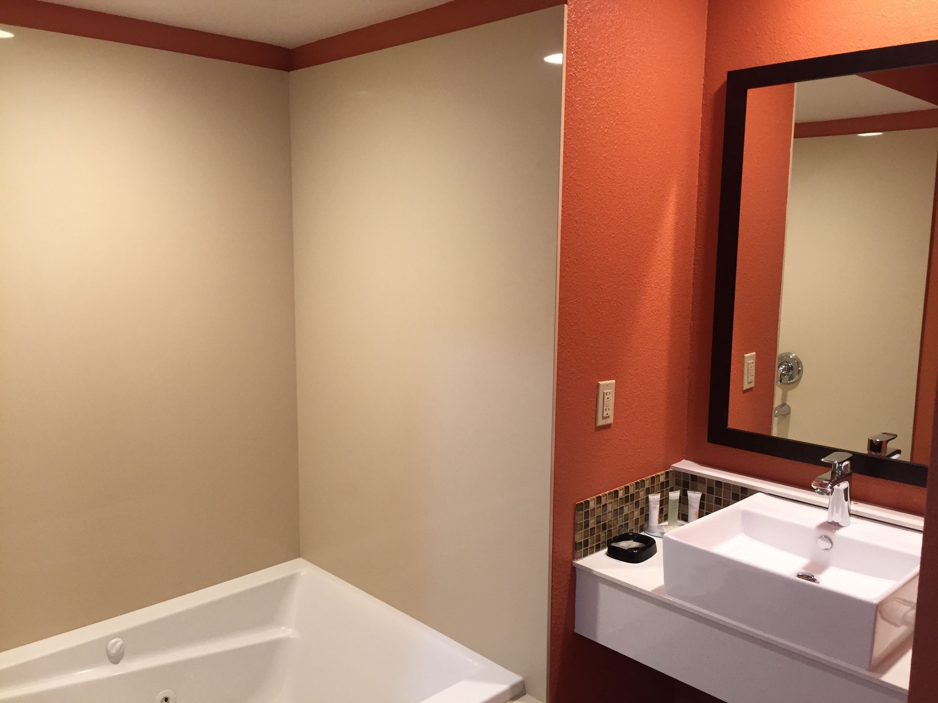 A modern bathroom with a bathtub, a sink, and a large mirror.