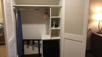 A walk-in closet with a hanging rack, shelves, and a small appliance.