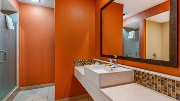 A bathroom with orange walls, a white sink, and a large mirror.