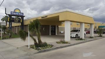 A Days Inn hotel with a yellow facade, palm trees, and a parking lot.
