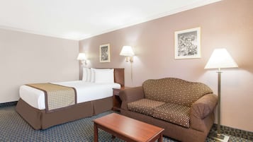 Habitación de hotel con cama, sofá, una mesita y dos lámparas de pared.