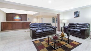 A hotel lobby with two leather sofas, a reception desk, and a glass coffee table with decorative items.