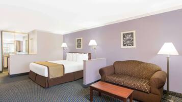 Una habitación de hotel con cama, sofá, una mesita y dos lámparas fijadas a la pared.