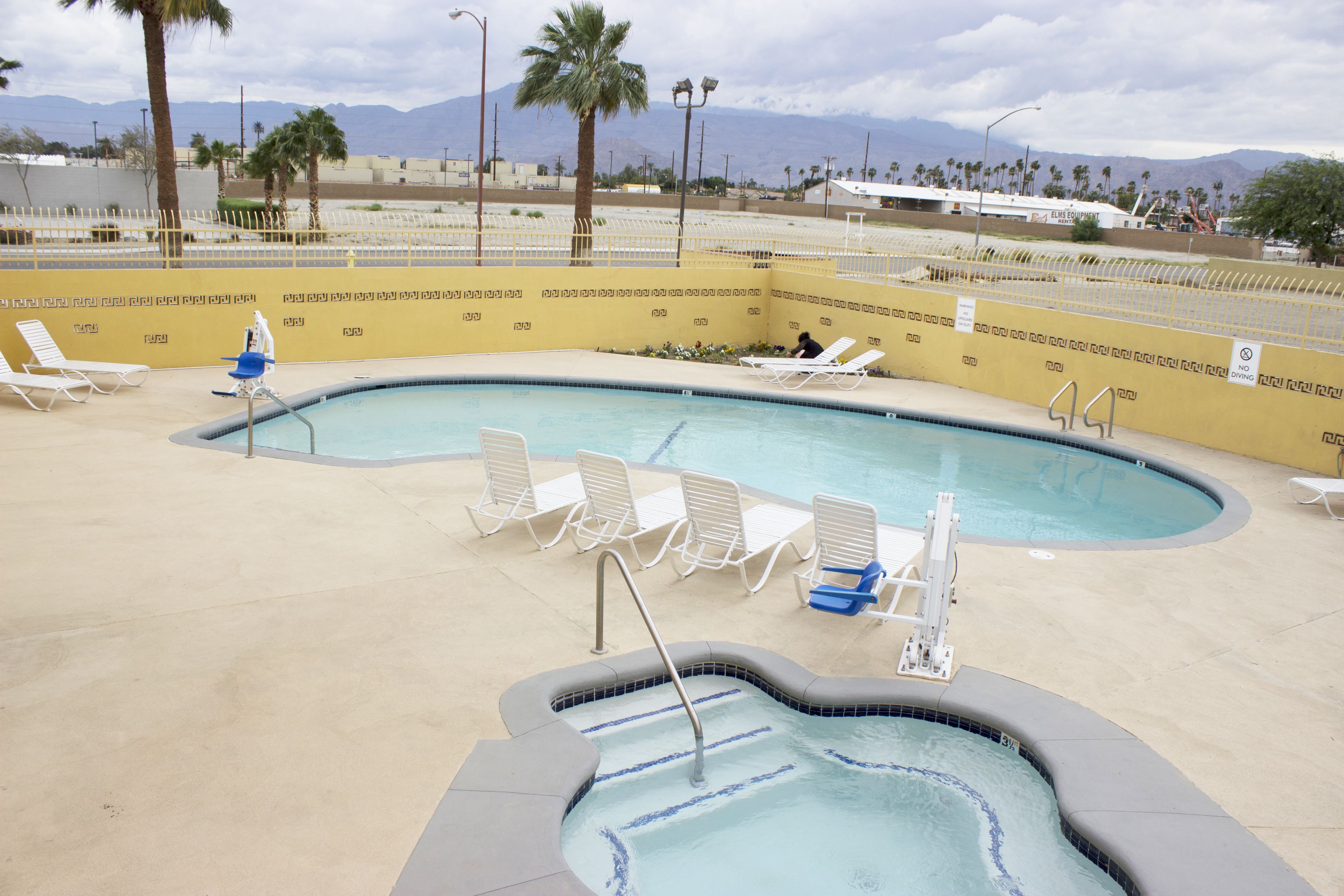 A swimming pool with lounge chairs and a hot tub.