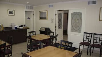 A dining area with a wooden table and chairs, a kitchen area with appliances, and a door with a 'PUSH' sign.