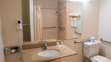 A bathroom with a sink, mirror, shower, toilet, and hand dryer.