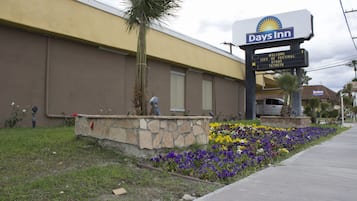 Ein Days Inn Hotel mit einem Steinkübel mit Blumen und einer Palme.