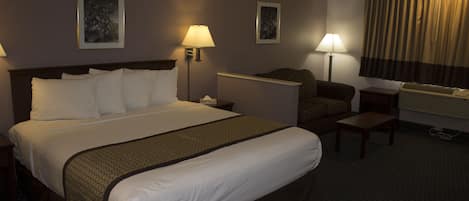 Habitación de hotel con una cama grande, dos mesitas de noche, un escritorio, una silla y dos lámparas de pared.