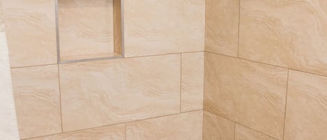A bathroom with a bathtub, a shower, and a tiled wall.