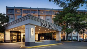 A hotel entrance with a covered area, signage, and a clear sky.