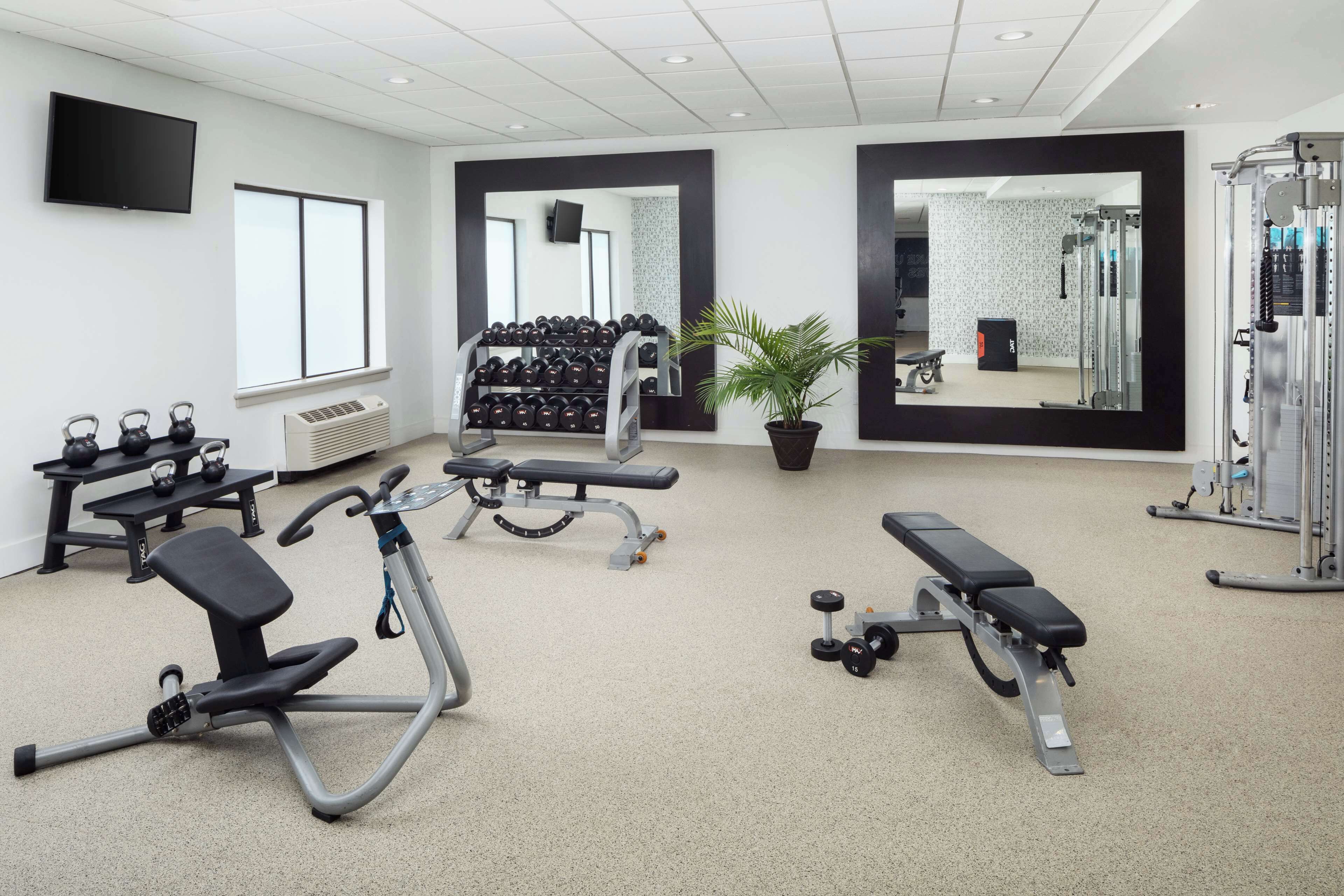 Ein Fitnessstudio mit verschiedenen Trainingsgeräten, darunter Laufbänder, Kurzhanteln und Kraftgeräte.
