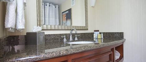 A bathroom with a granite countertop, a sink, and a mirror.