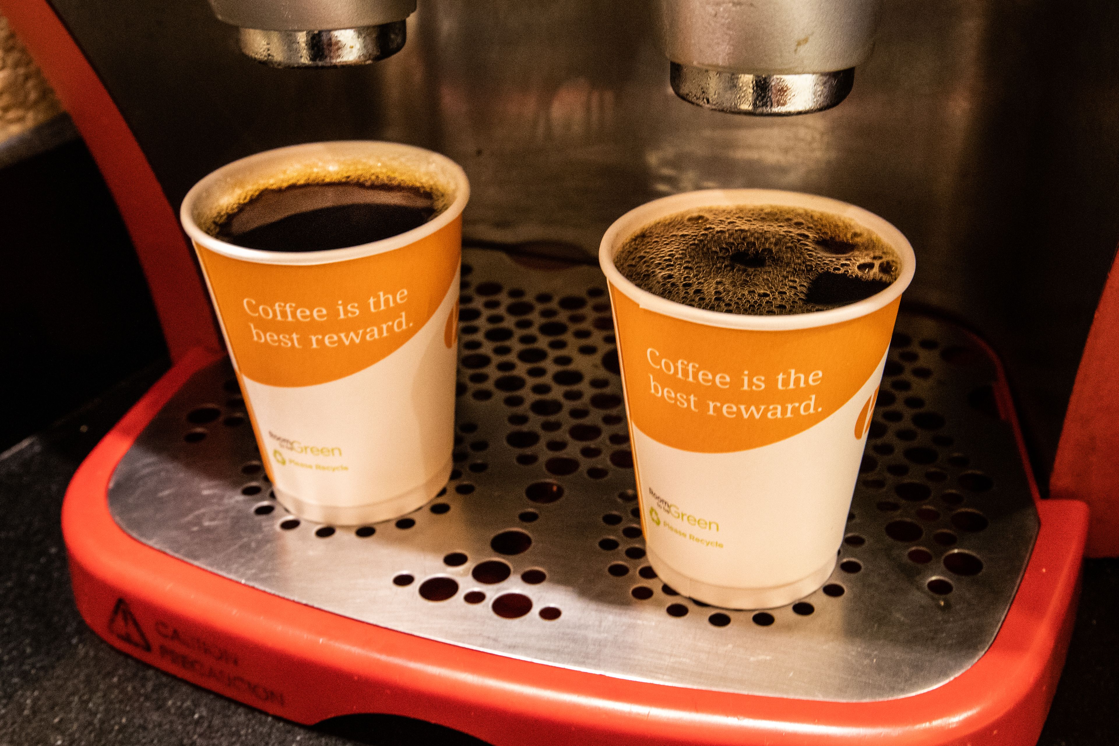 Deux tasses à café sur une machine à café, avec l'inscription : « Le café est la meilleure des récompenses. »