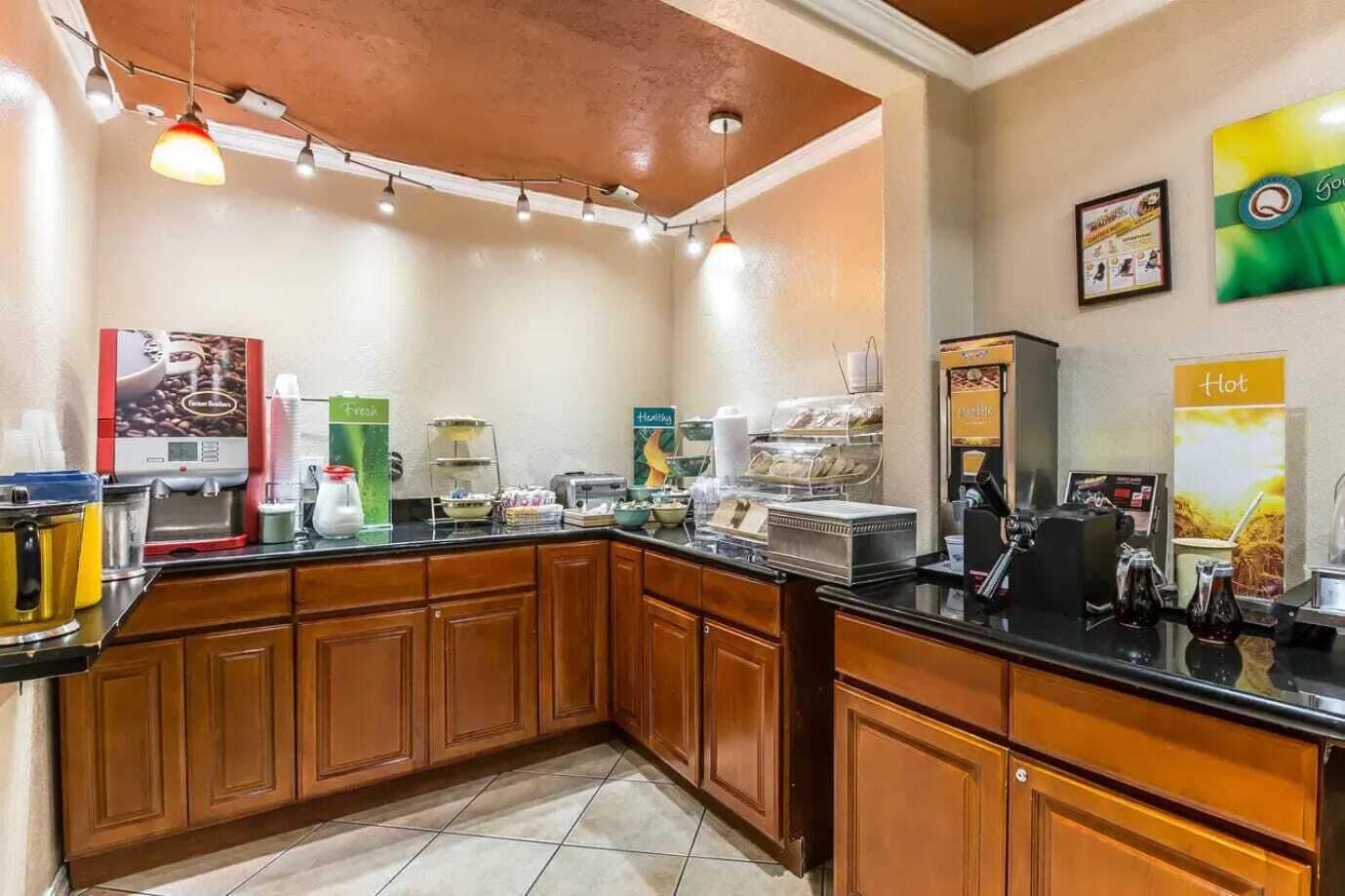 Zona de petit esmorzar amb màquines de cafè, presentació de fruita i racó de begudes calentes.