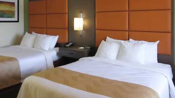A hotel room with two beds, a nightstand, a lamp, and a painting on the wall.