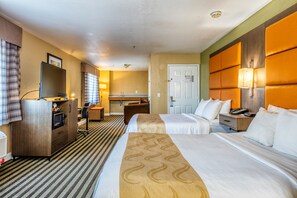 A hotel room with two beds, a desk, a microwave, a chair, and a bathroom visible through an open door.