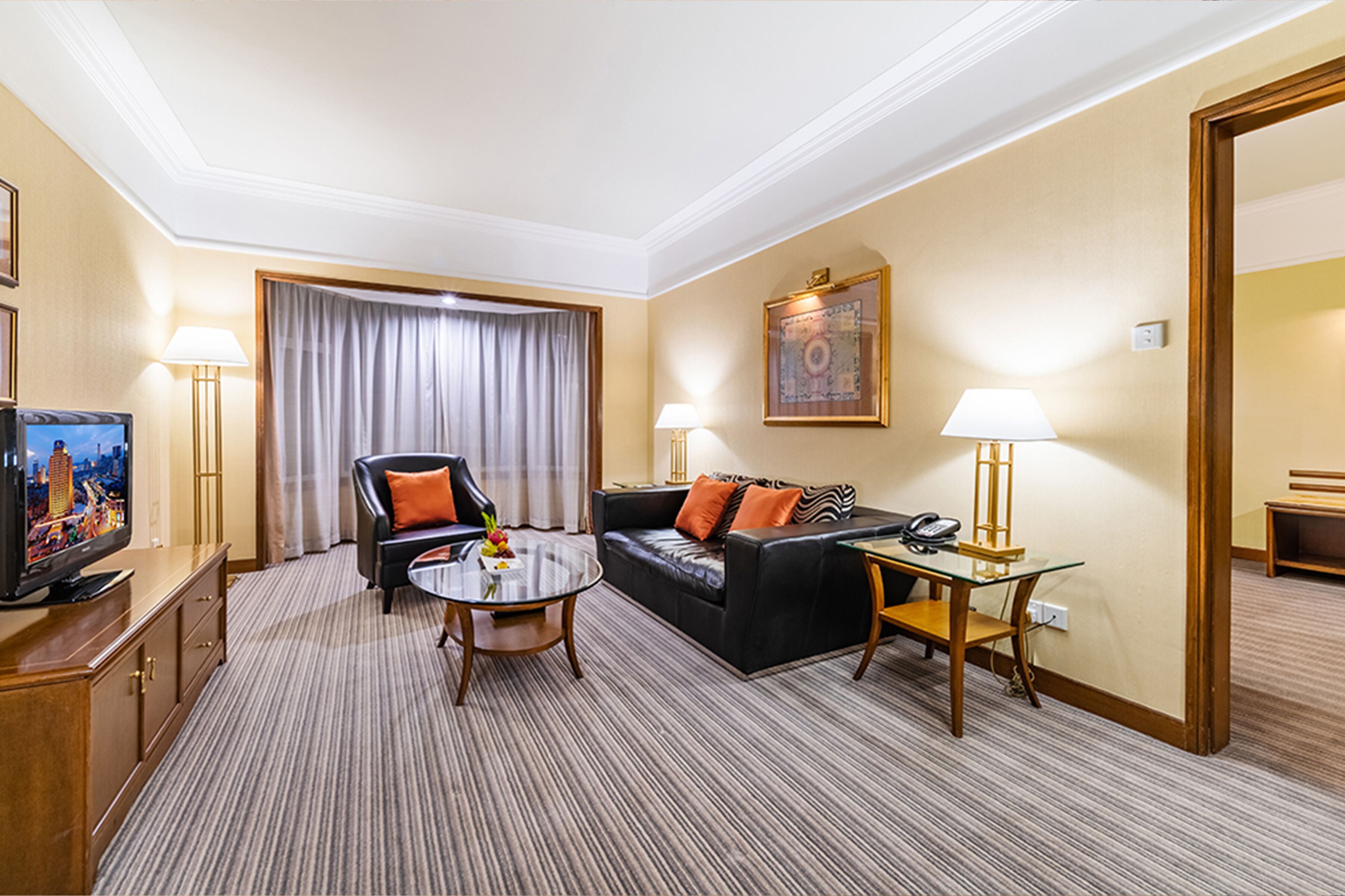 Habitación de hotel con sofá, sillón y una mesita de noche con lámpara.