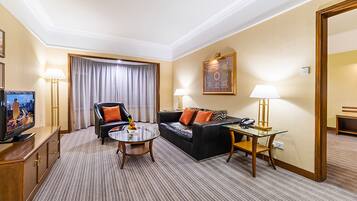 Habitación de hotel con sofá, sillón y una mesita de noche con lámpara.