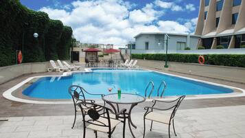 Una piscina al aire libre de temporada, sombrillas