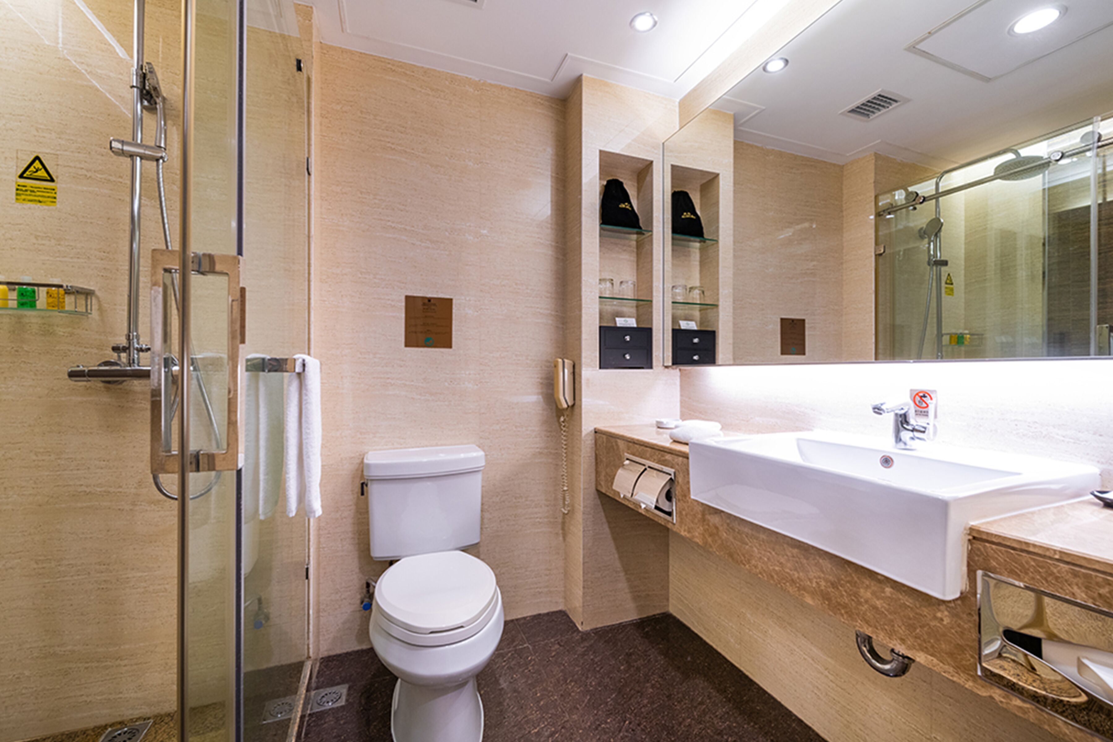 A modern bathroom with a glass shower enclosure, a white toilet, a sink with a mirror above it, and a towel rack.