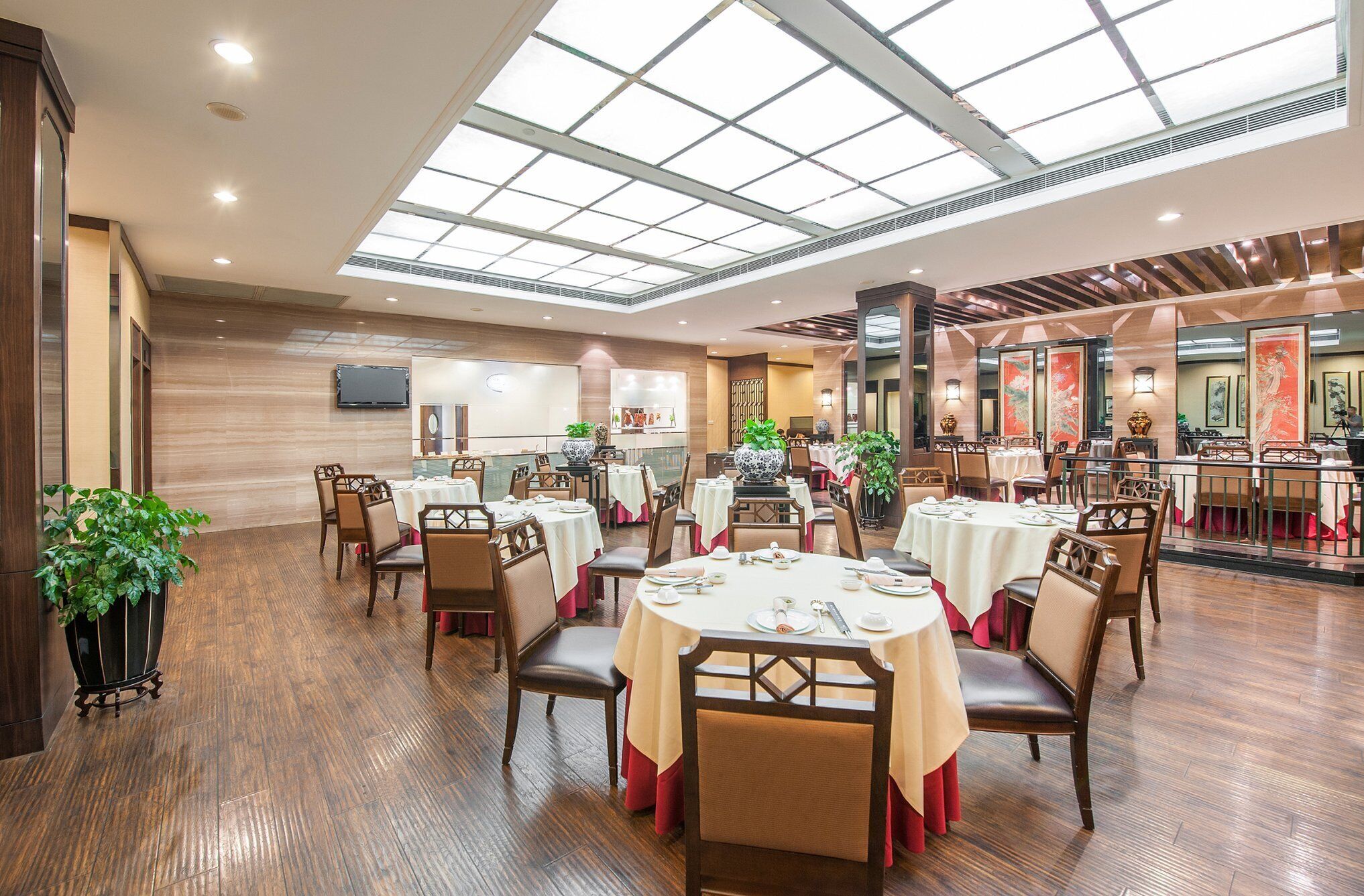 Un vaste espace dédié à la salle à manger, avec des tables rondes, des chaises et un plafond haut doté de lucarnes.