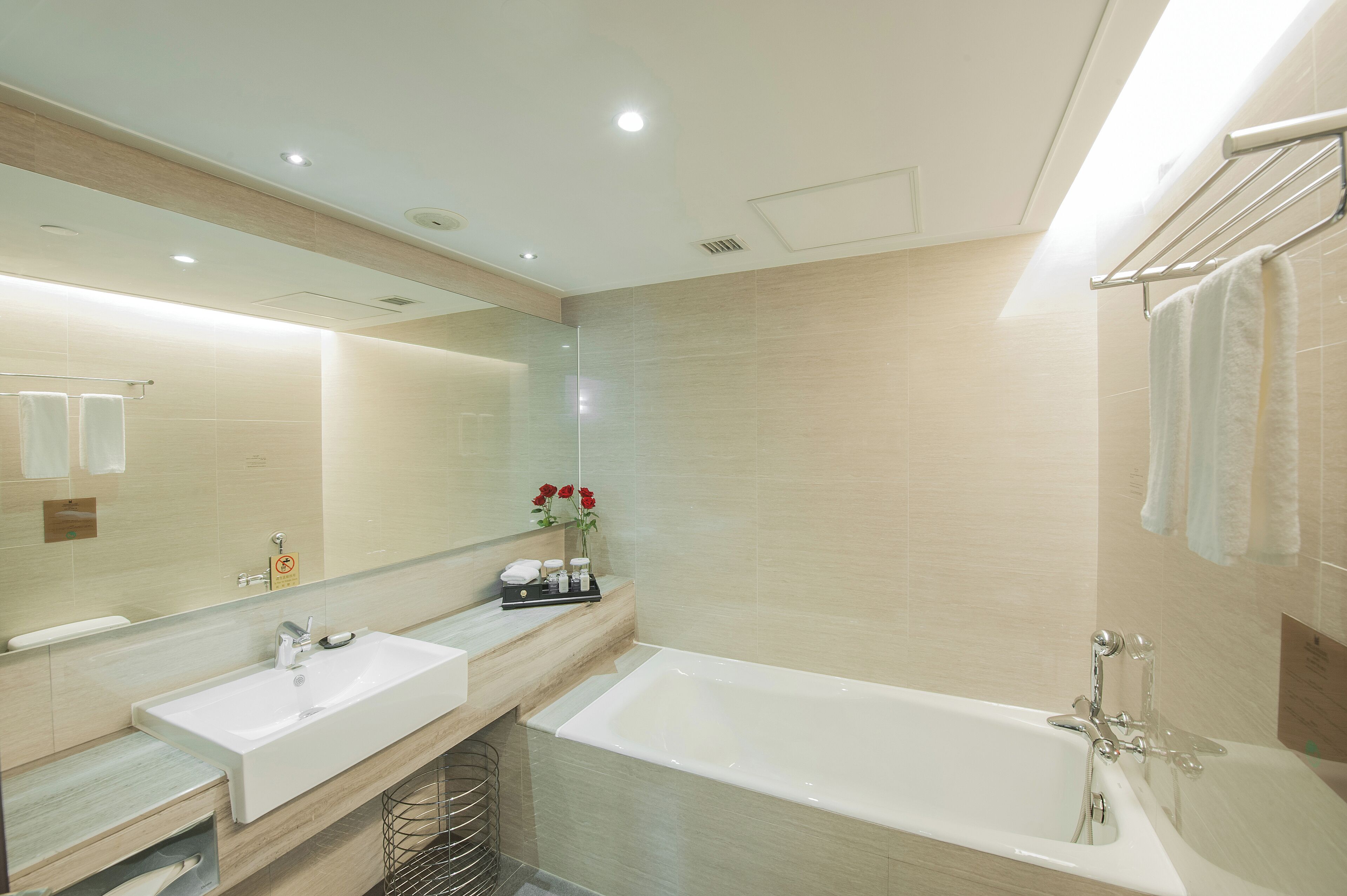 A modern bathroom with a large mirror, two sinks, a bathtub, and a towel rack.