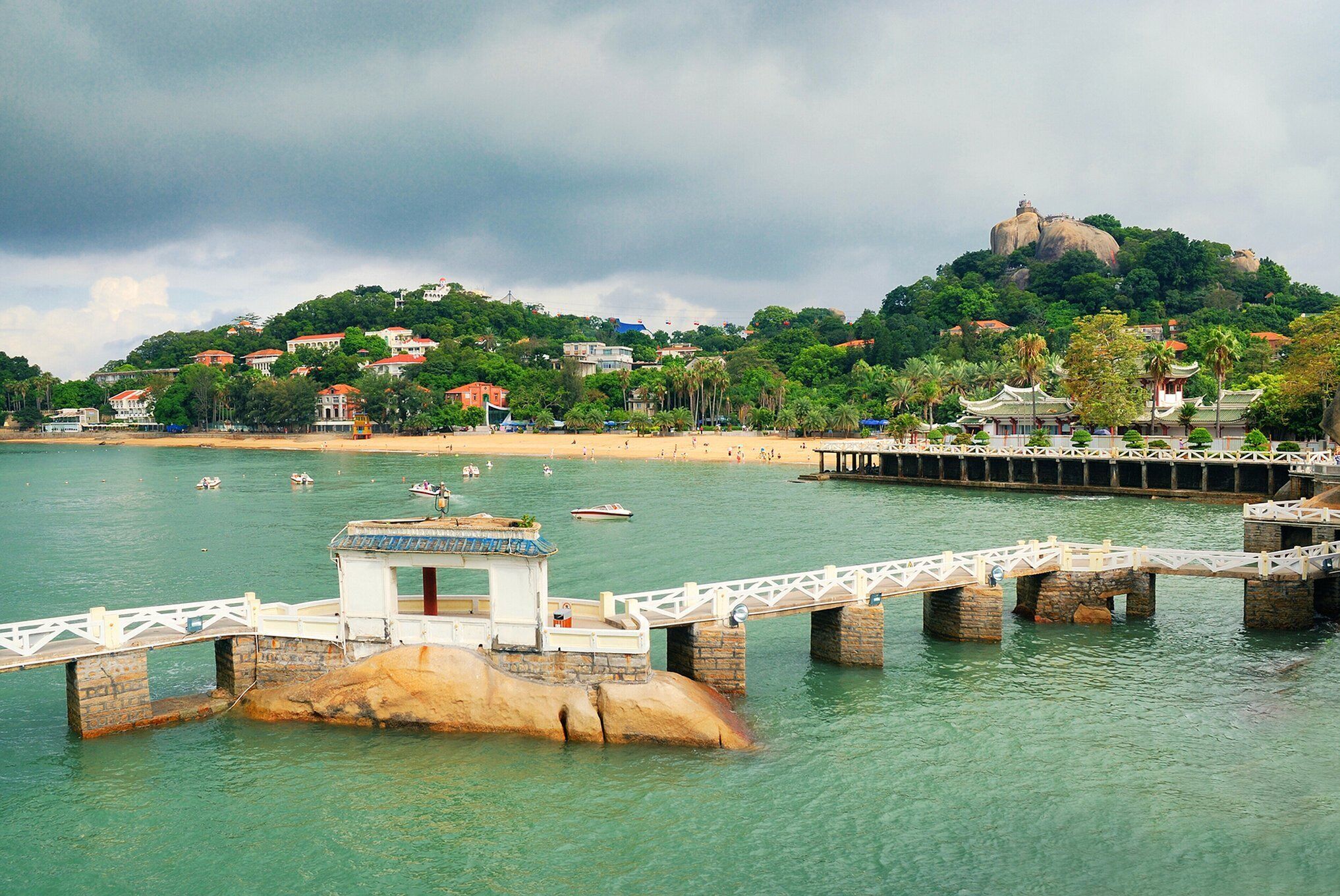 A coastal area with a bridge, water, and buildings on a hill.