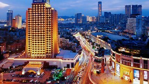 Een hoog hotel met een opvallend "Millennium" bord, omringd door een drukke stedelijke omgeving met meerdere hoge gebouwen en een goed verlichte straat.