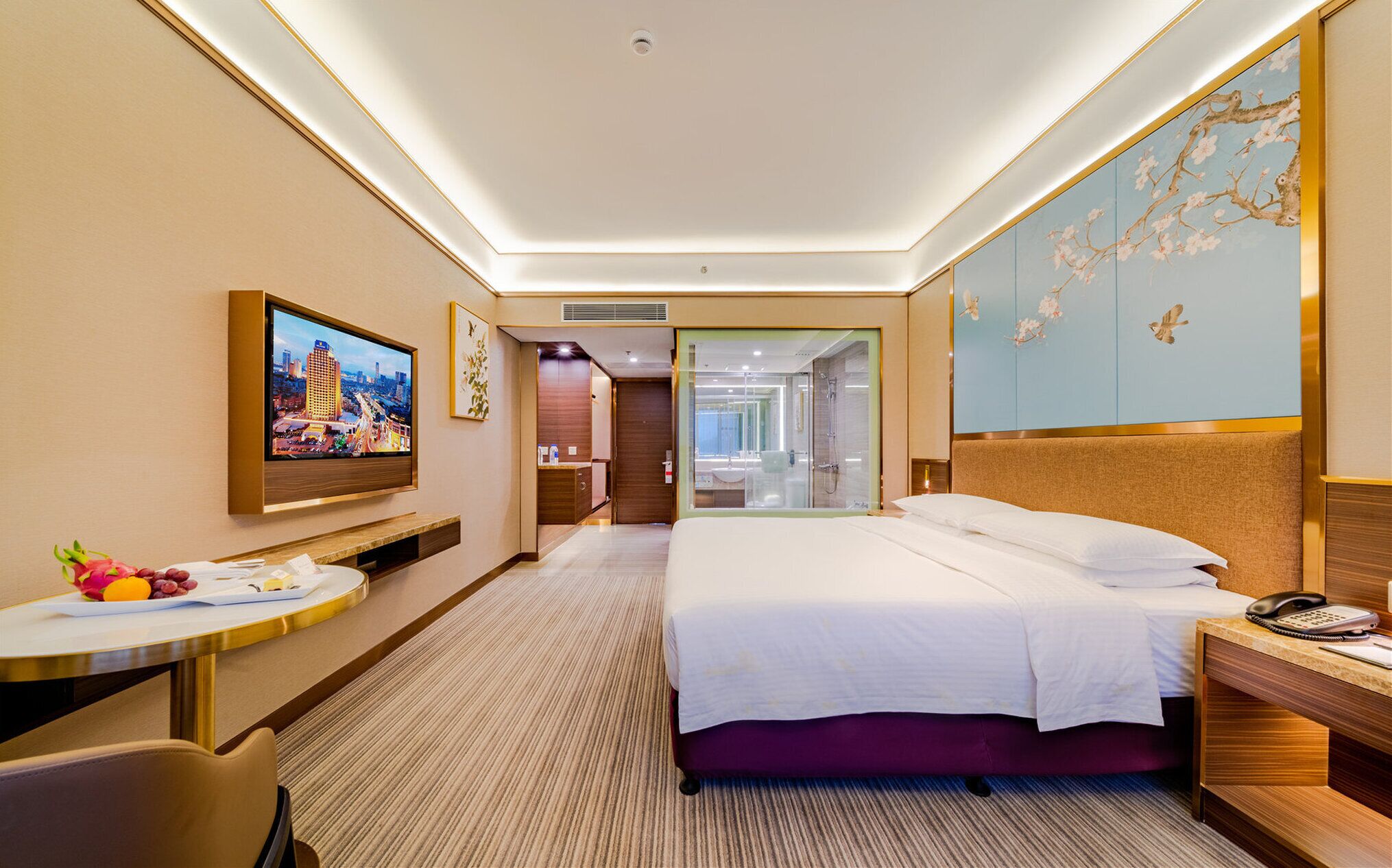 Una camera d'albergo con un letto, un comodino, una TV e vista sulla città.