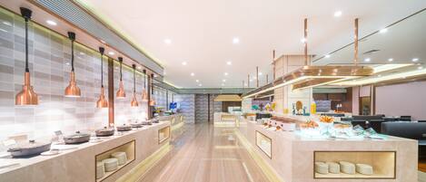 A modern restaurant with a long counter, copper pendant lights, and a variety of dishes displayed.