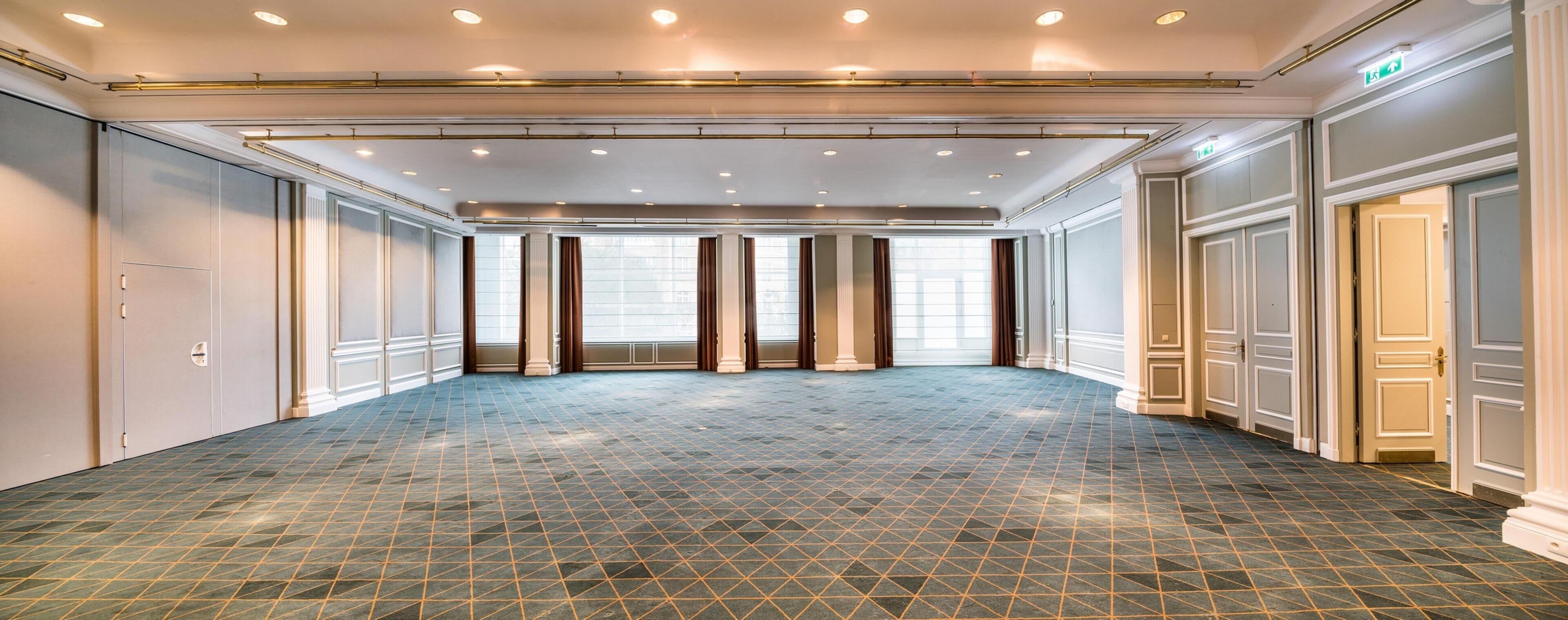 Un hall d’hôtel spacieux, doté d’un sol à motifs géométriques, de grandes fenêtres et d’un design moderne au niveau du plafond.