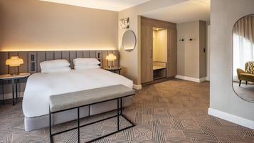 A hotel room with a large bed, bedside lamps, a mirror, and a patterned carpet.