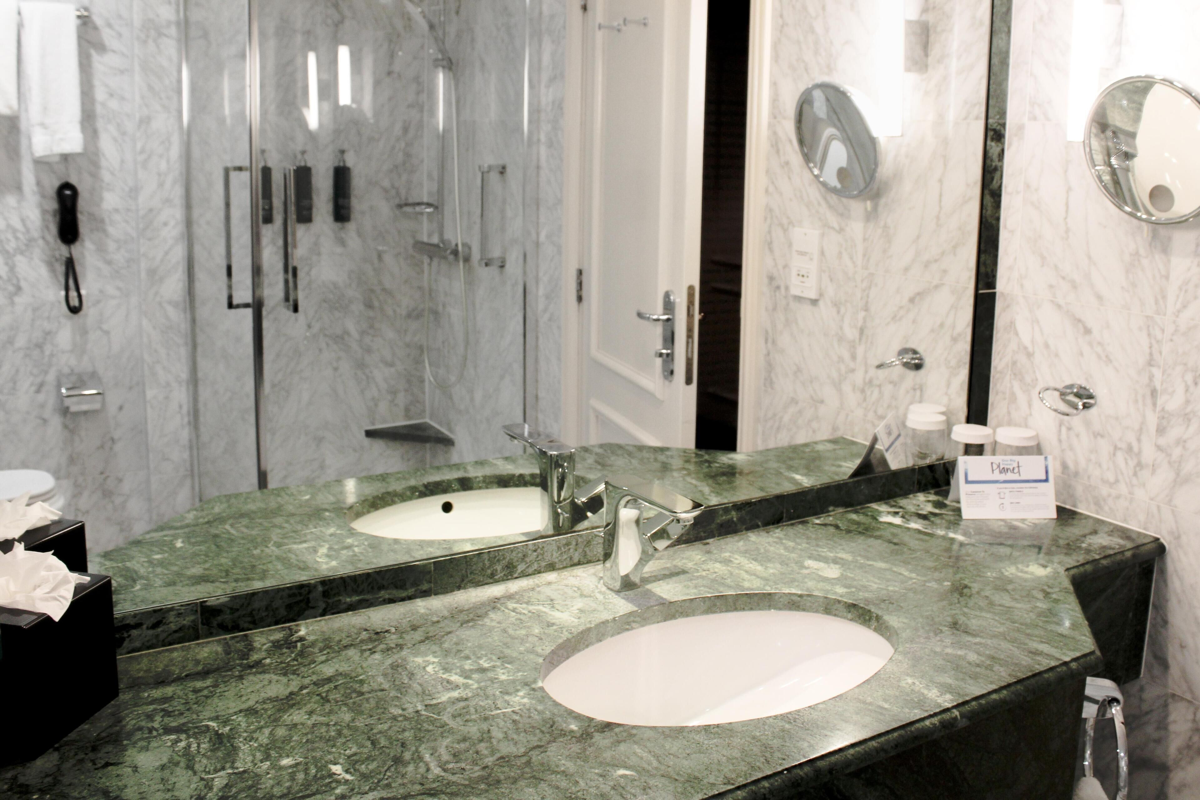 A bathroom with two sinks, a mirror, and a shower.