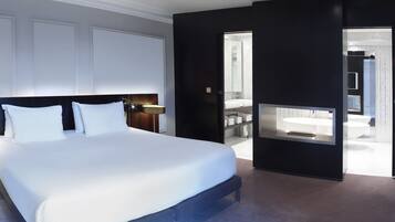 A modern hotel room with a large bed, a TV, and a view into the bathroom.